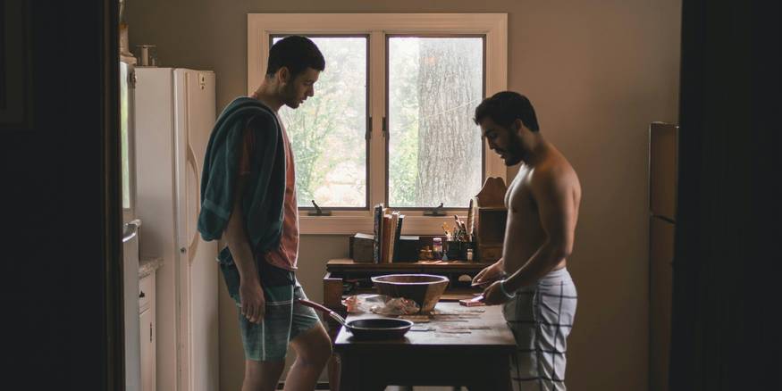 Two Michigan roommates sit at a kitchen table drafting their roommate agreement