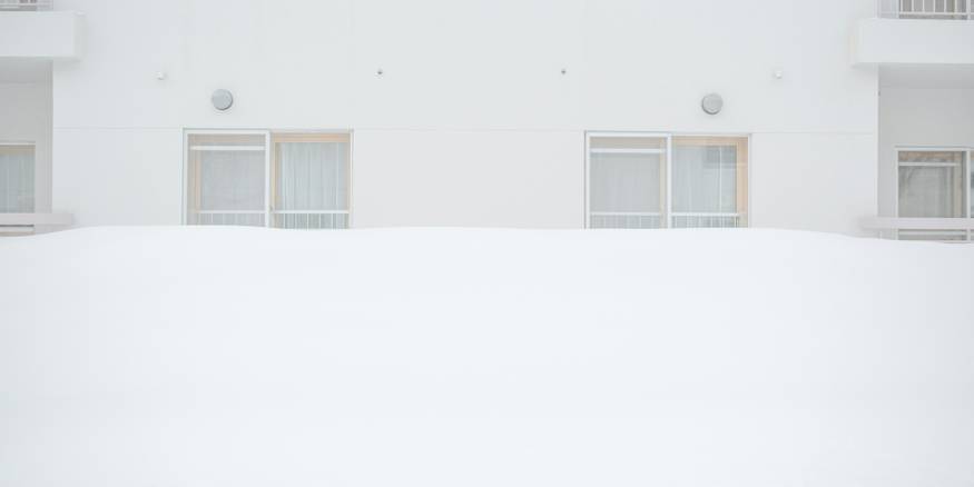 Tenant checks apartment radiator while snow falls outside
