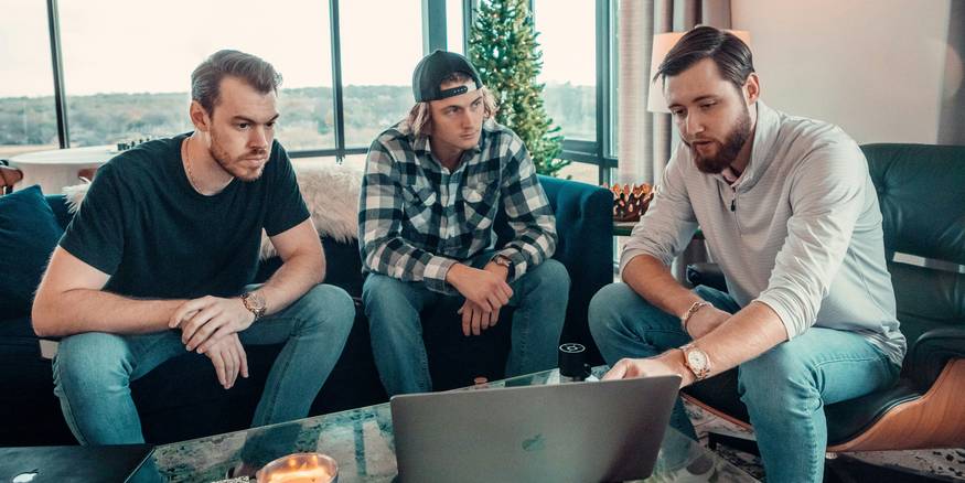 Three Michigan college students reviewing off-campus apartment listings on a laptop